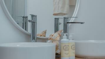 A bathroom with a round mirror, two sinks, and a towel rack.
