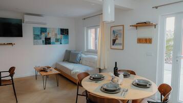 Un espacio habitable moderno con comedor, sofá, televisor y obras de arte en las paredes.