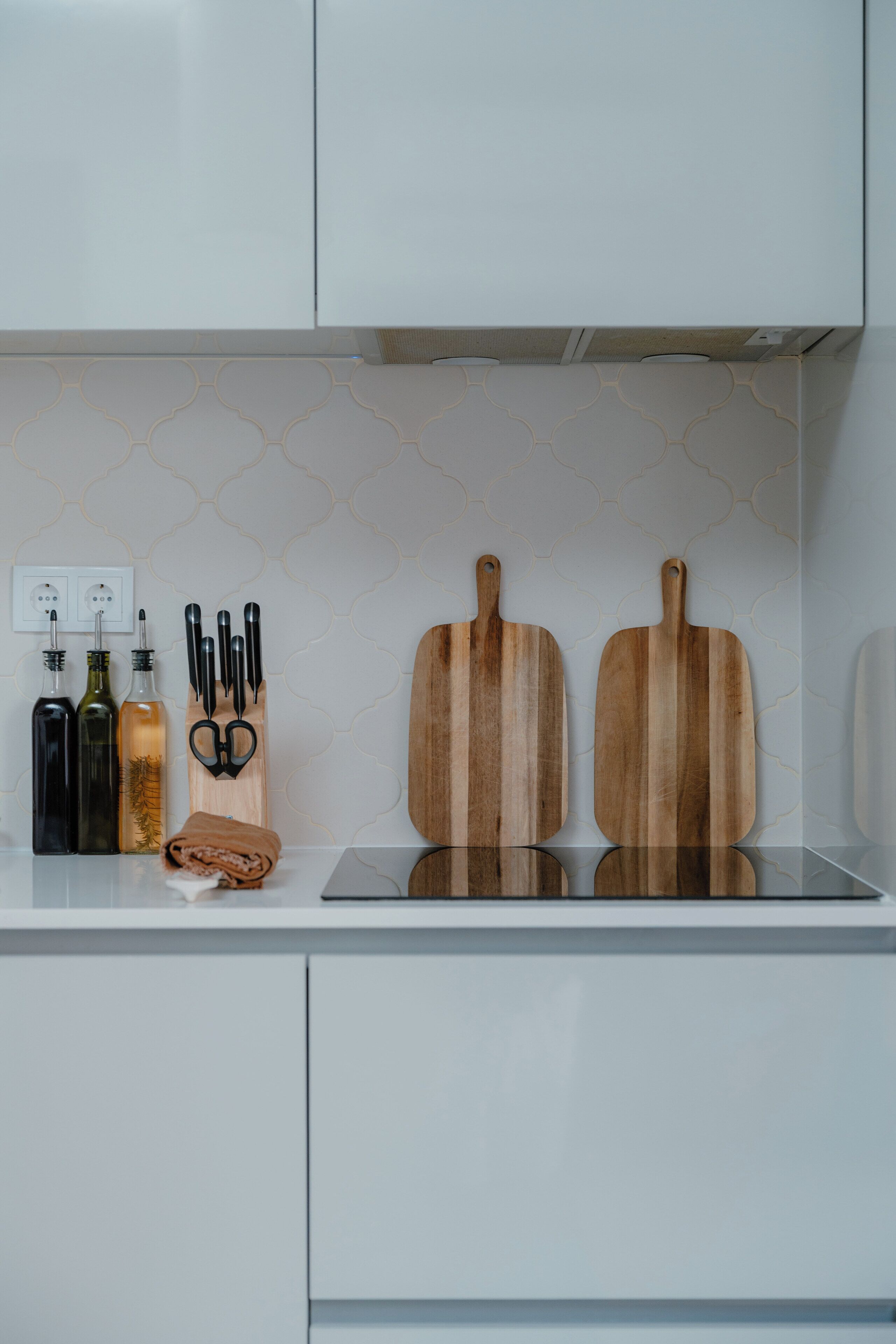 A kitchen counter with two wooden cutting boards, a knife set, and three bottles.