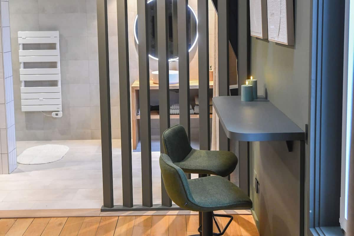 A modern interior with a wooden floor, a bar area with a stool, a wall-mounted circular light, and a radiator.