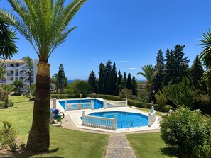 A pool area with two pools, surrounded by palm trees and a view of the sea. - 50 - Apt. in Riviera del Sol / Mijas (Mijas Costa)