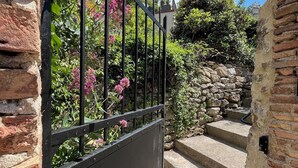 Una escalera de piedra que conduce a una entrada protegida por un portón de metal.