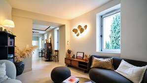 Una sala de estar moderna con un sofá, una mesa de centro, una estantería y un comedor al fondo.