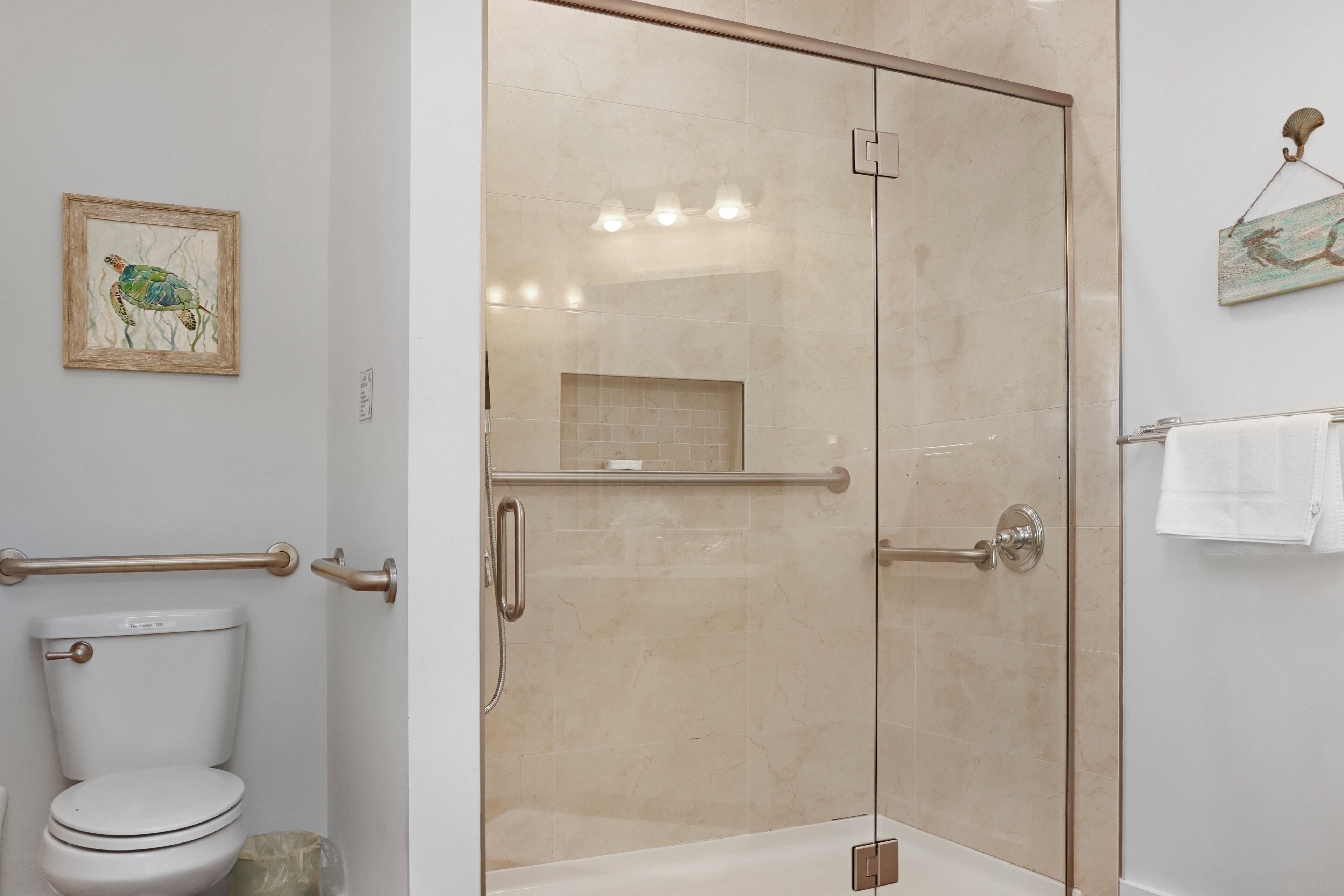Une salle de bain moderne avec une douche à parois de verre, des toilettes et un petit lavabo.