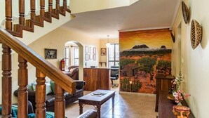 Un vaste espace de vie agrémenté d’un escalier en bois, d’une grande fresque murale et d’un comptoir d’accueil.