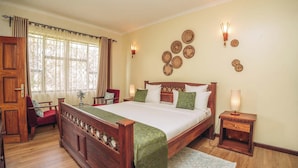 Une chambre avec un lit en bois, une chaise, une table de chevet et des œuvres d’art décoratives accrochées au mur.