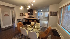 Une cuisine moderne dotée d’un îlot central, d’un coin bar et d’un espace repas avec une table en verre et des chaises rembourrées.