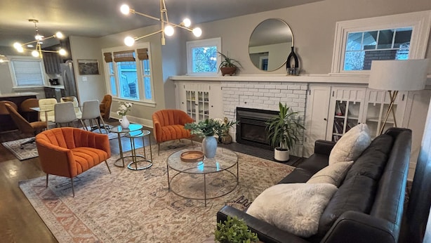 Un salon avec une cheminée, un canapé, une table basse et un coin repas avec des chaises.