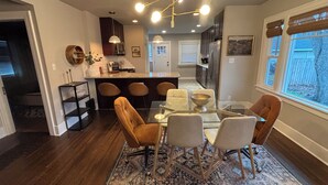 Une cuisine moderne dotée d’un îlot central, de tabourets de bar et d’un coin repas avec une table et des chaises en verre.
