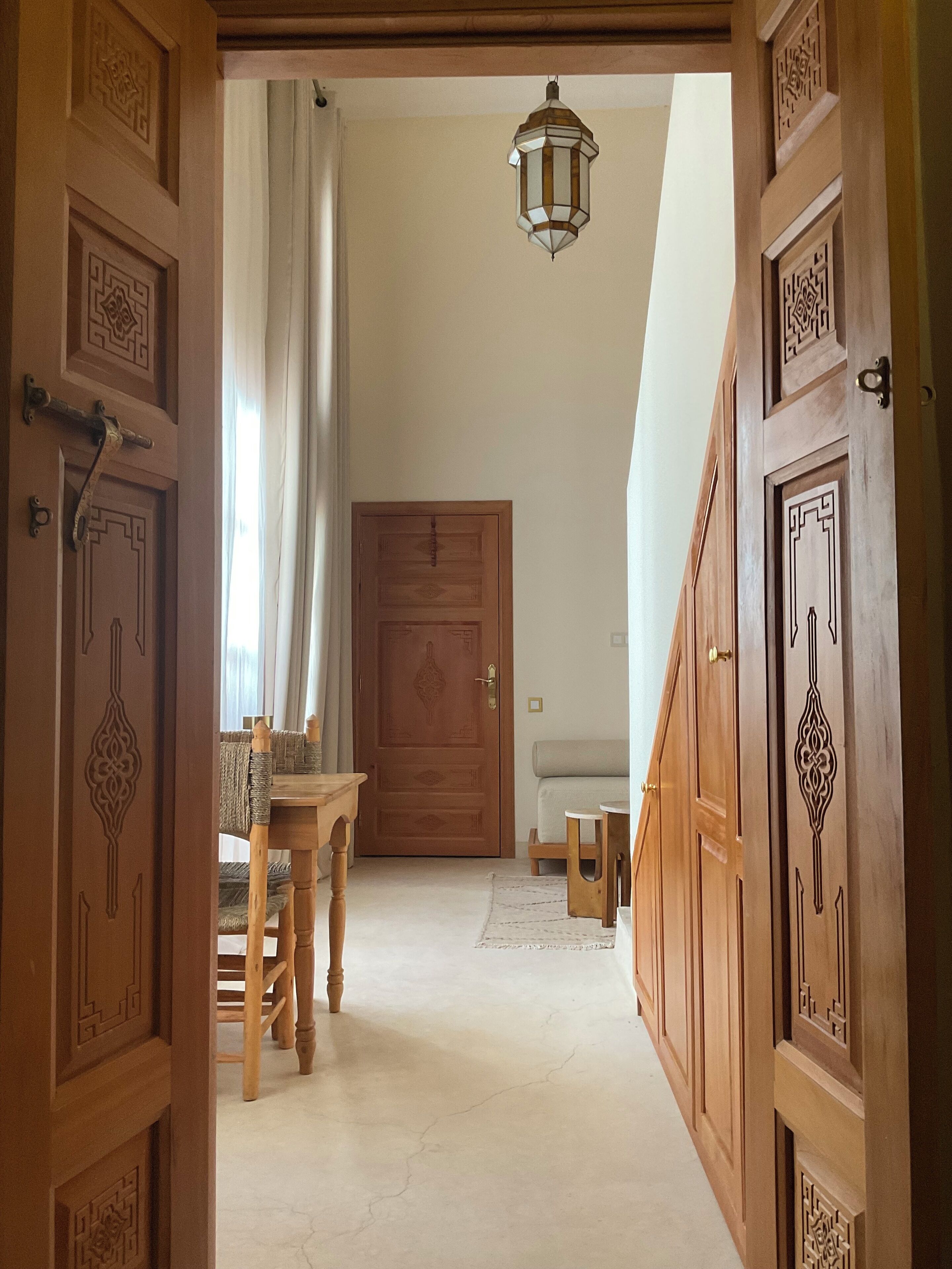 Un pasillo con puertas de madera, una mesa de comedor y un banco.
