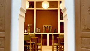 An arched doorway leading to a room with a patterned ceiling, a chandelier, and a table with chairs. - Riad Al Muhandiz (Marrakech)