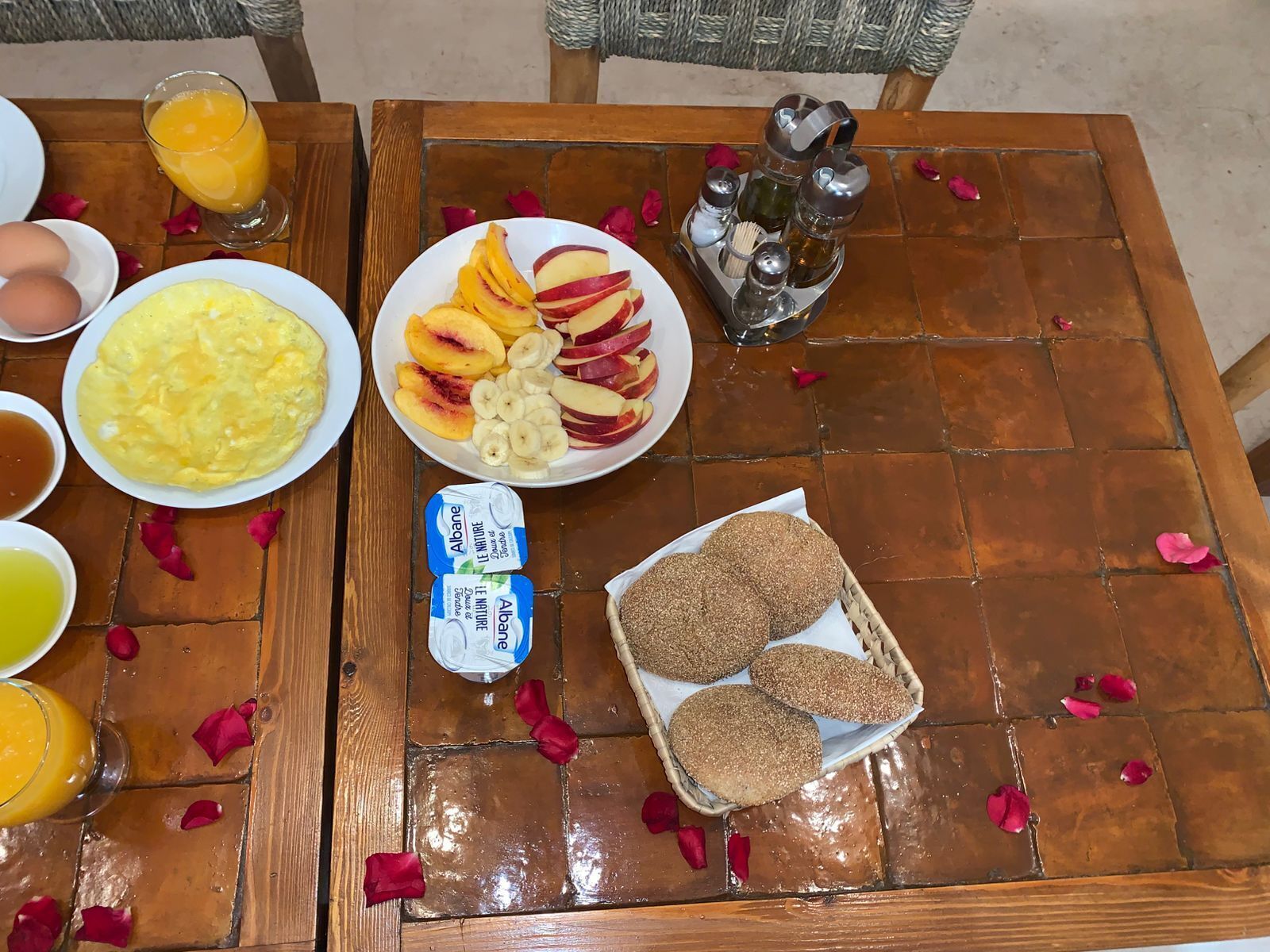 Una mesa de desayuno con platos de huevos, fruta, pan y jugo.