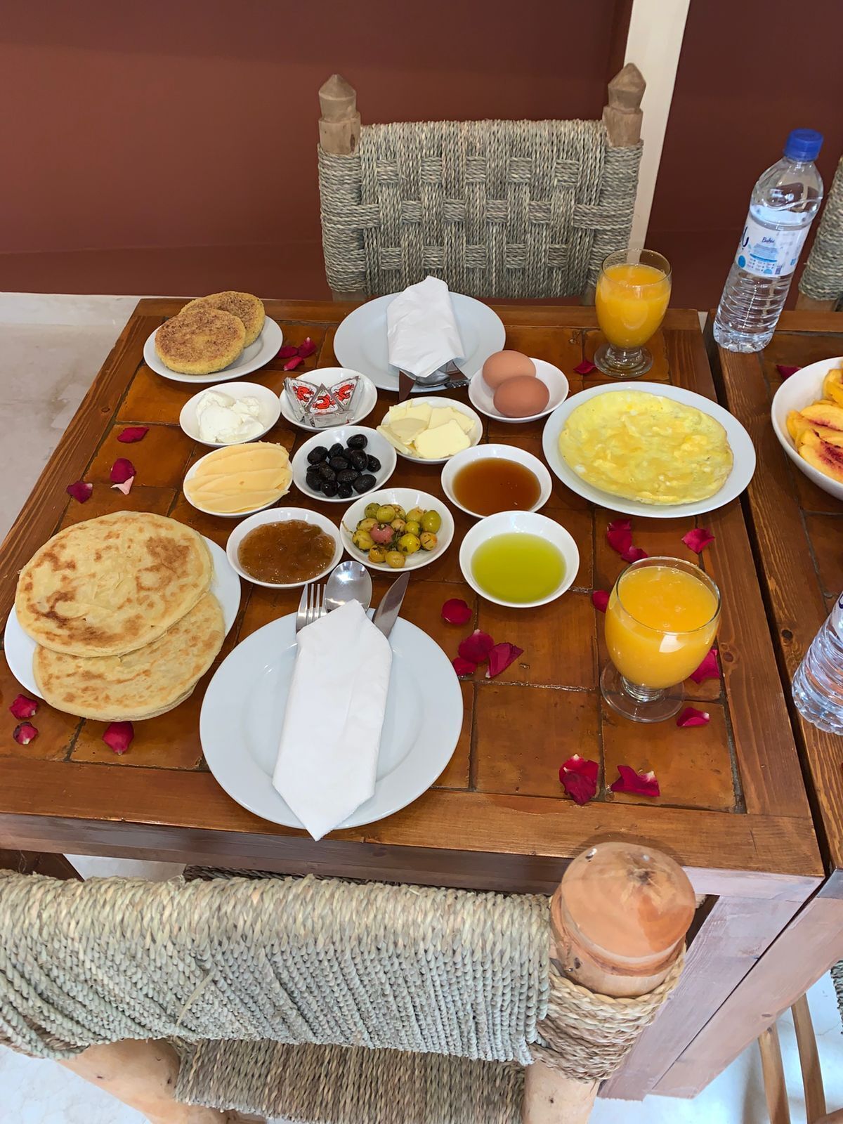A breakfast table with various dishes, including pancakes, eggs, and fruit, along with beverages and condiments.
