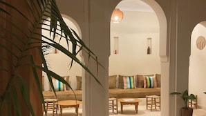A spacious interior with high ceilings, arched doorways, and a central seating area with a sofa and chairs. - Riad Al Muhandiz (Marrakech)