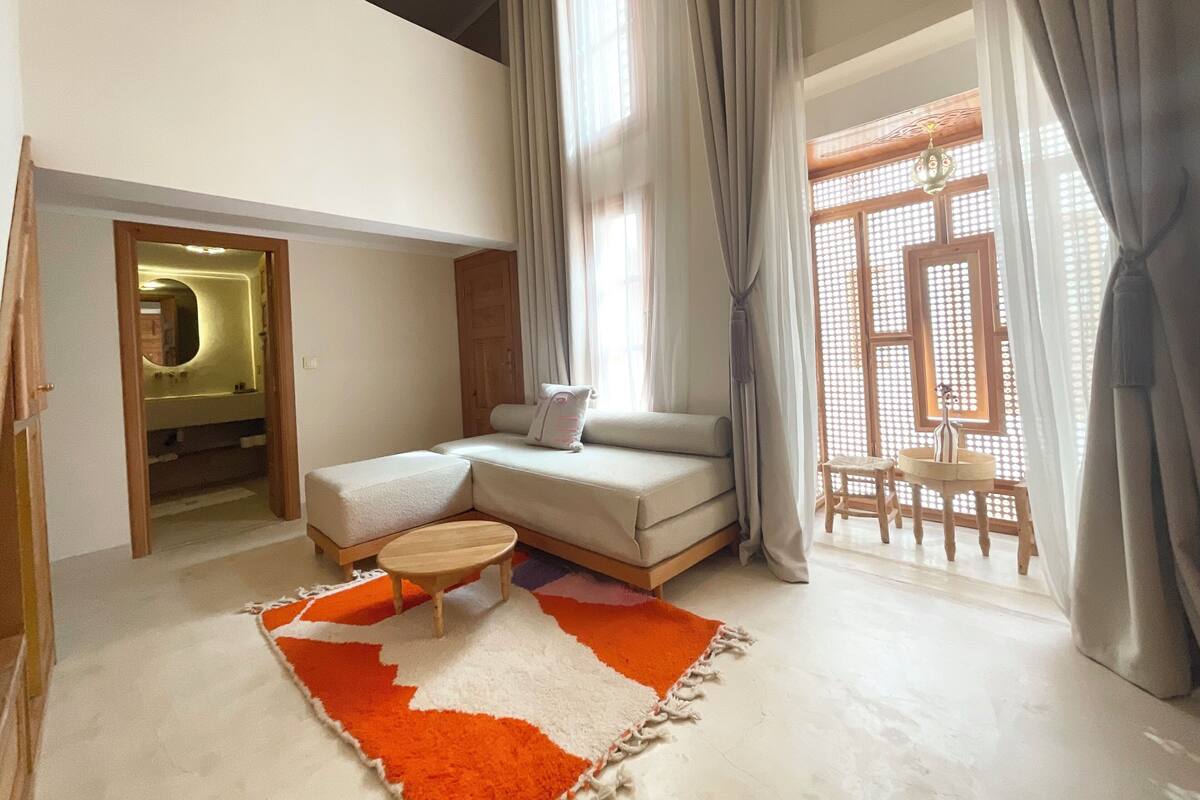 A modern living room with a sofa, a small round table, and a colorful rug.