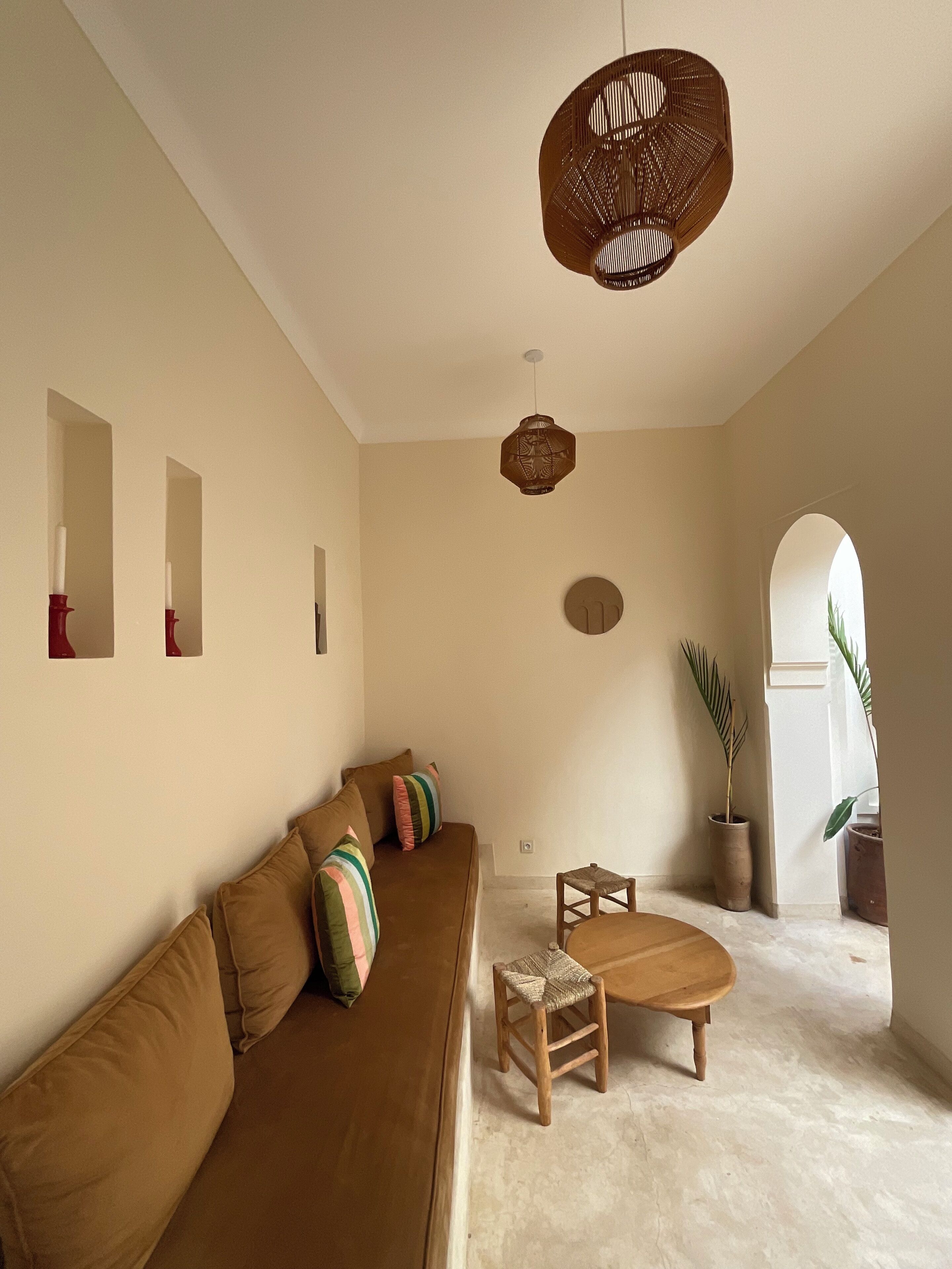 A spacious living room with a brown sofa, a wooden coffee table, and a hanging woven light fixture.