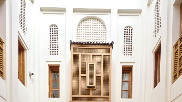 A courtyard with white walls, wooden doors, and a central seating area with a sofa and curtains. - Riad Al Muhandiz (Marrakech)