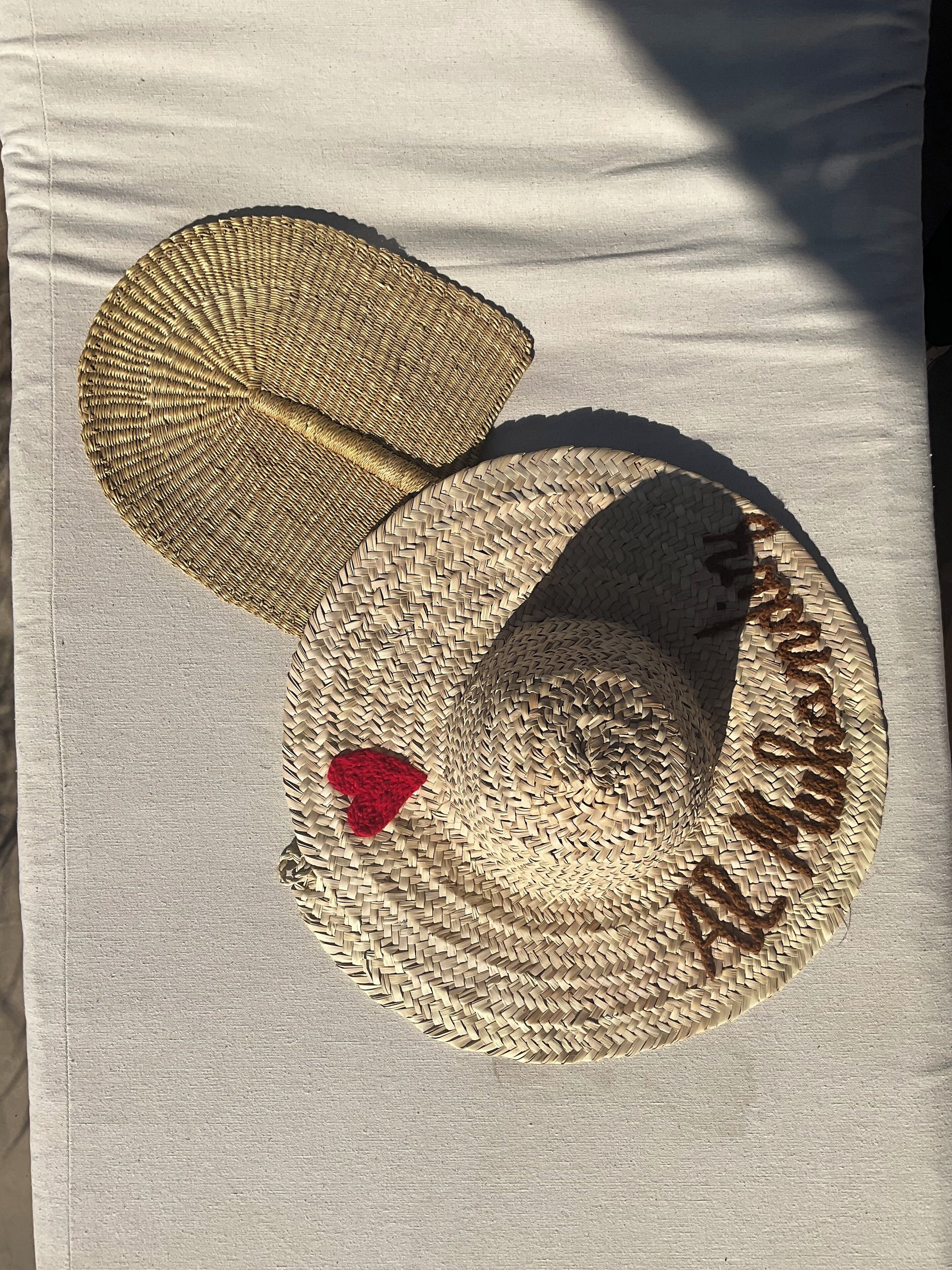 Un sombrero tejido con un parche en forma de corazón y el texto 'Happy Birthday' sobre una superficie de tela.