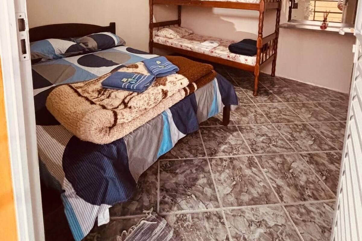 A room with bunk beds, a heater, a window with a view, and a tiled floor.