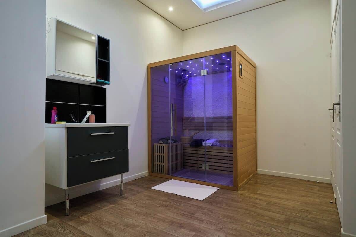 Quarto compacto com roupeiro embutido, um pequeno espaço de estar com um banco e um claraboia acima.