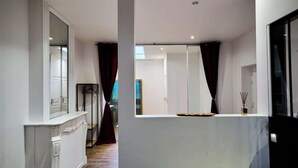 A modern interior with a white vanity, a mirror, and a dark curtain. - Baignoire Blanéo & Sauna, 10 minutes de la gare (Tourcoing)