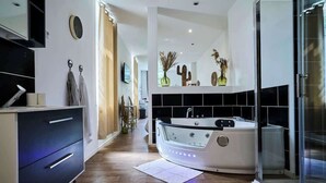 A modern bathroom with a freestanding bathtub, a shower area, and a vanity with a mirror and towel rack. - Le nid douillé, balnéo proche gare (Tourcoing)