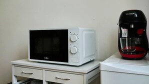 A microwave and a coffee maker on a white countertop. - Le nid douillé, balnéo proche gare (Tourcoing)
