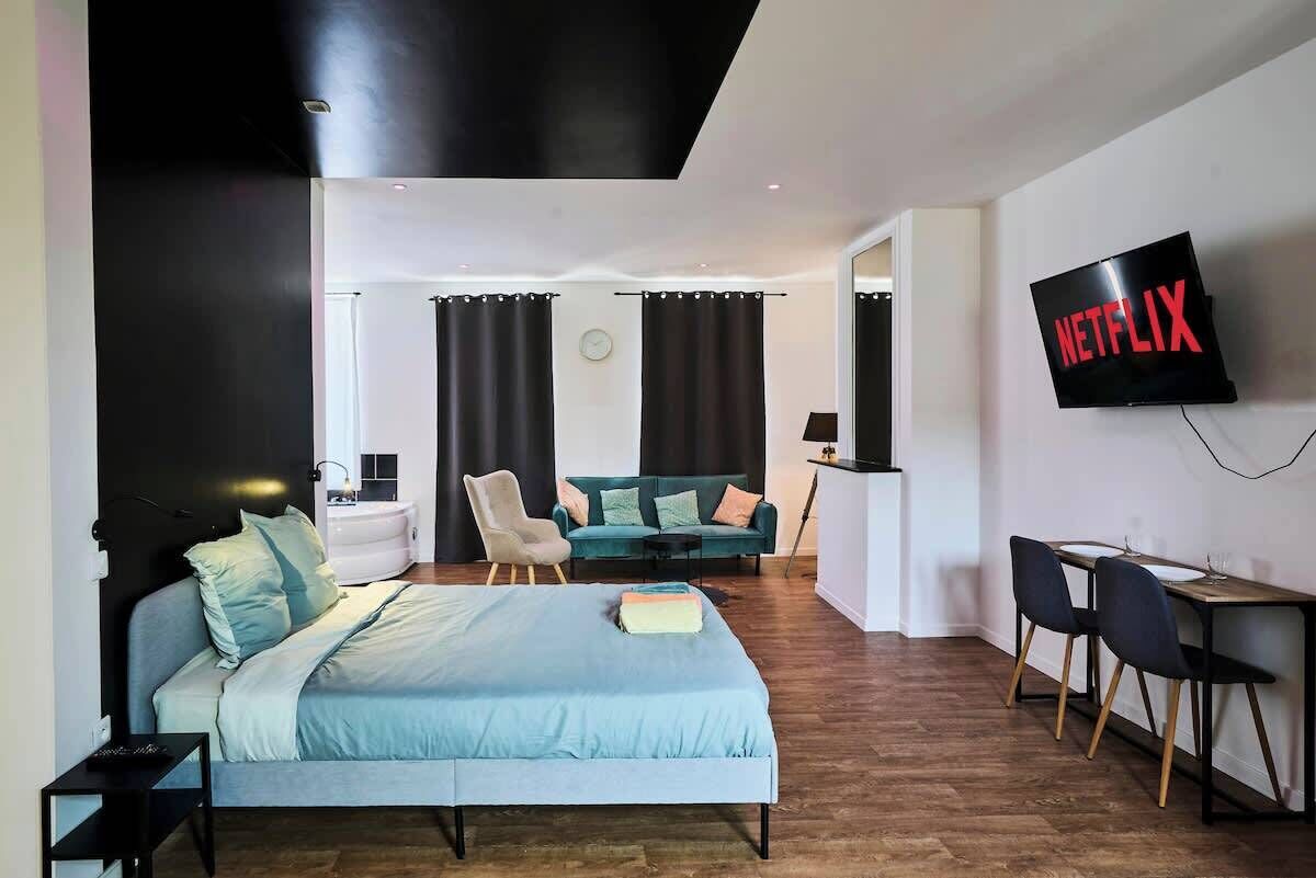A modern hotel room with a bed, a desk, a chair, a TV, and a sofa.