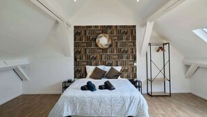 Een slaapkamer met een groot bed, een boekenkast en een dakraam.