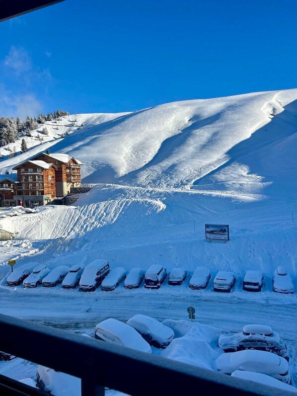 Estación de esquí nevada con un edificio y autos estacionados.