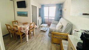 A cozy living area with a dining table, wooden chairs, a sofa, and a coffee machine. - Apartment les Oursons, 5 persons (La Plagne Tarentaise)