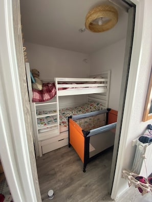 Habitación con literas, ventilador de techo, un osito de peluche y una cesta colgante.