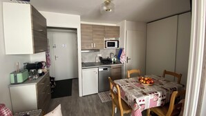 A compact kitchen with a microwave, sink, and a small dining area with a table set for two. - Apartment les Oursons, 5 persons (La Plagne Tarentaise)