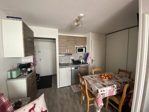 Une cuisine compacte équipée d’un four à micro-ondes, d’un évier et d’un petit coin repas avec une table dressée pour deux personnes.