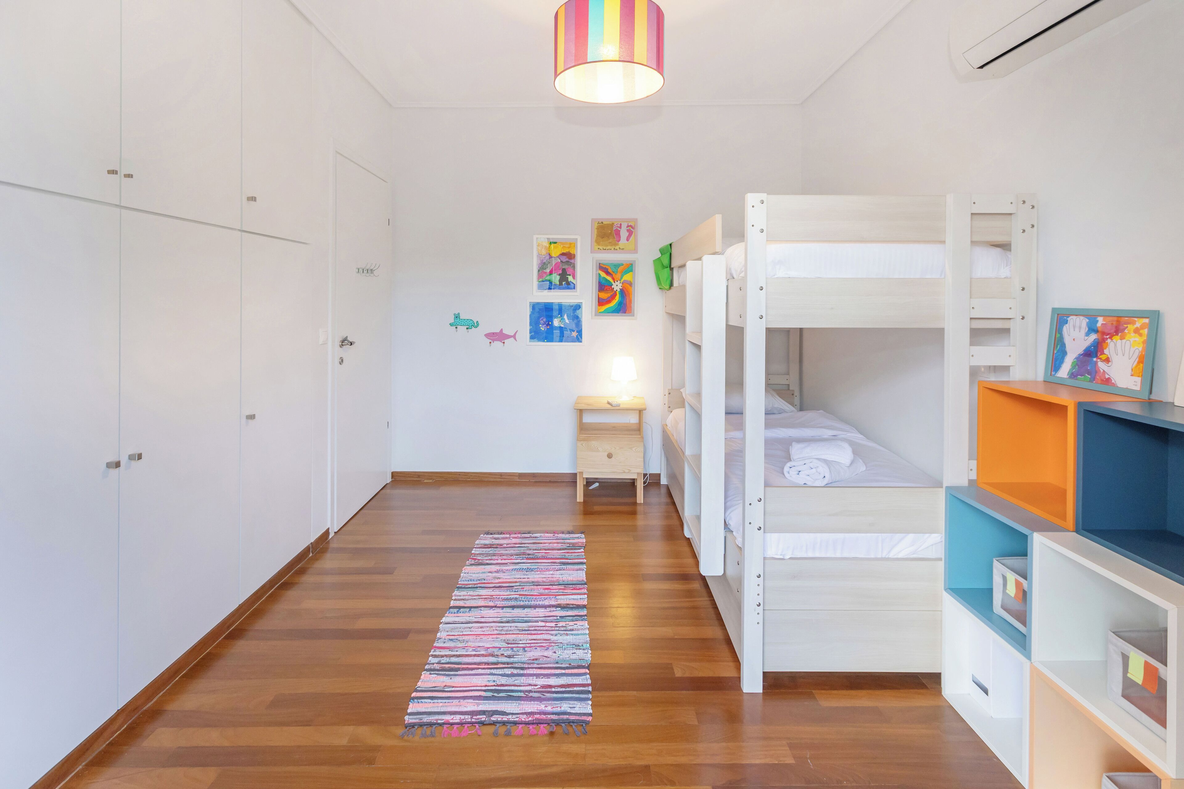 A child’s bedroom with bunk beds, a small desk, and colorful artwork on the walls.