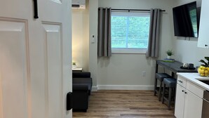 A modern kitchen with a wooden floor, a dining area with a table and chairs, and a TV mounted on the wall.