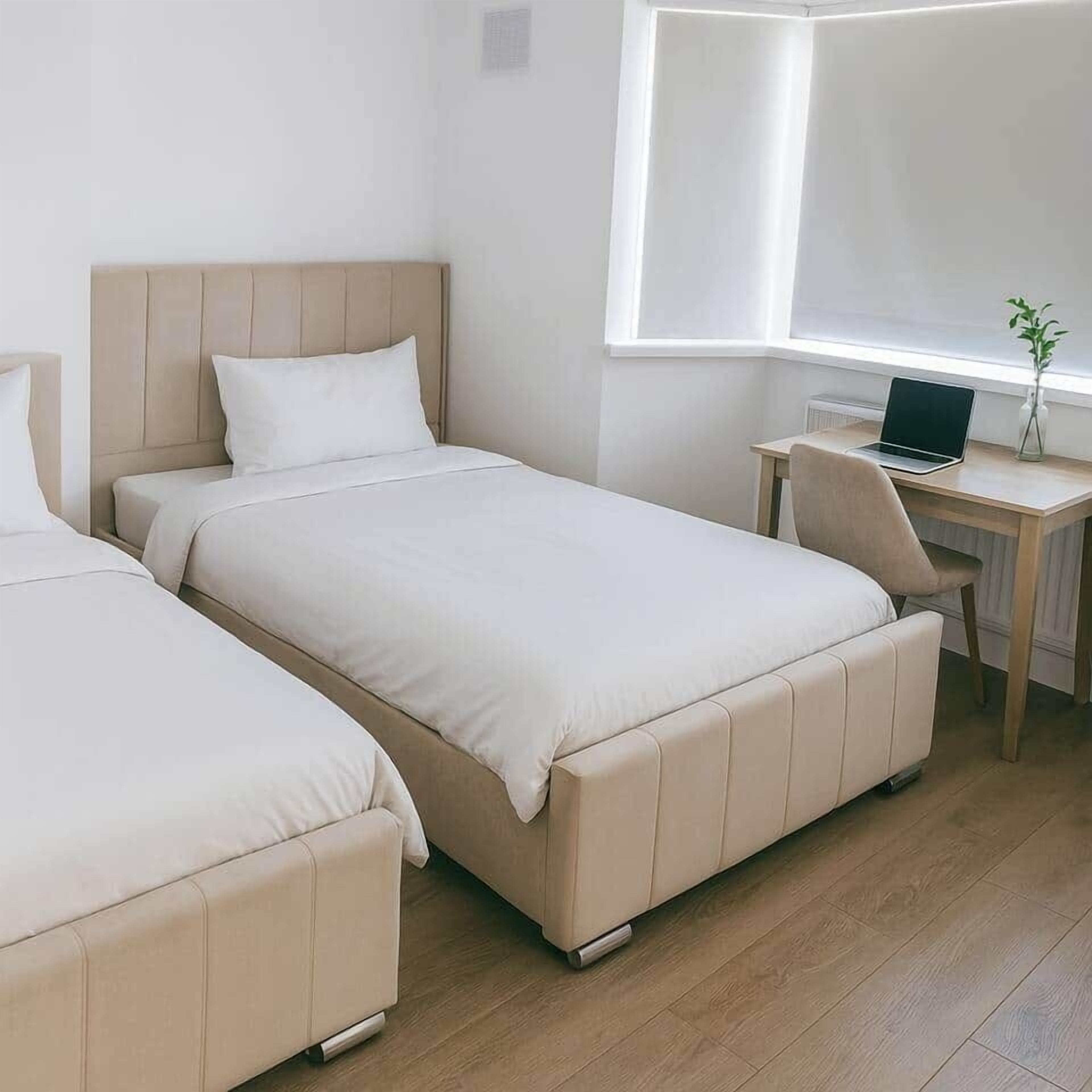 A bedroom with two beds, a desk, and a laptop.