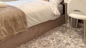 A modern bedroom with a large bed, a bedside table, a chair, a wall-mounted mirror, and a decorative chandelier. - Modern 4-Bed House • Sleeps 9 •Free Parking, Leeds (Leeds)