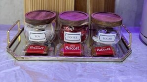 Three glass jars with wooden lids labeled 'TEA,' 'COFFEE,' and 'SUGAR,' each containing a Biscoff biscuit. - Modern 4-Bed House • Sleeps 9 •Free Parking, Leeds (Leeds)