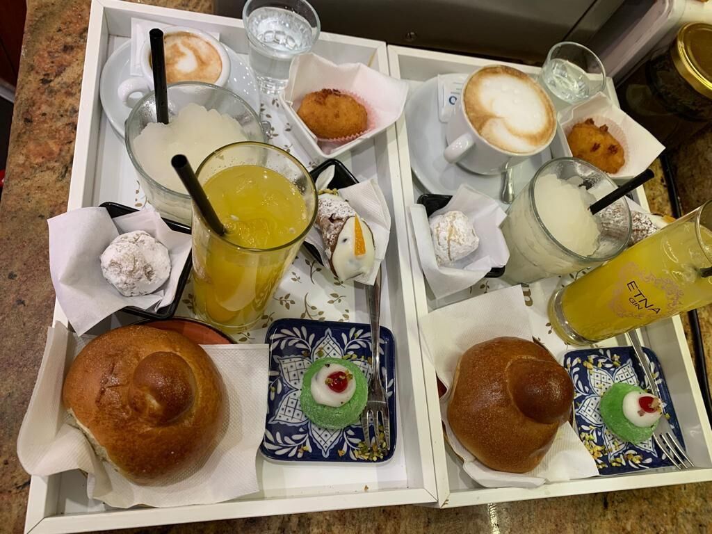 A breakfast tray with pastries, drinks, and a coffee cup.