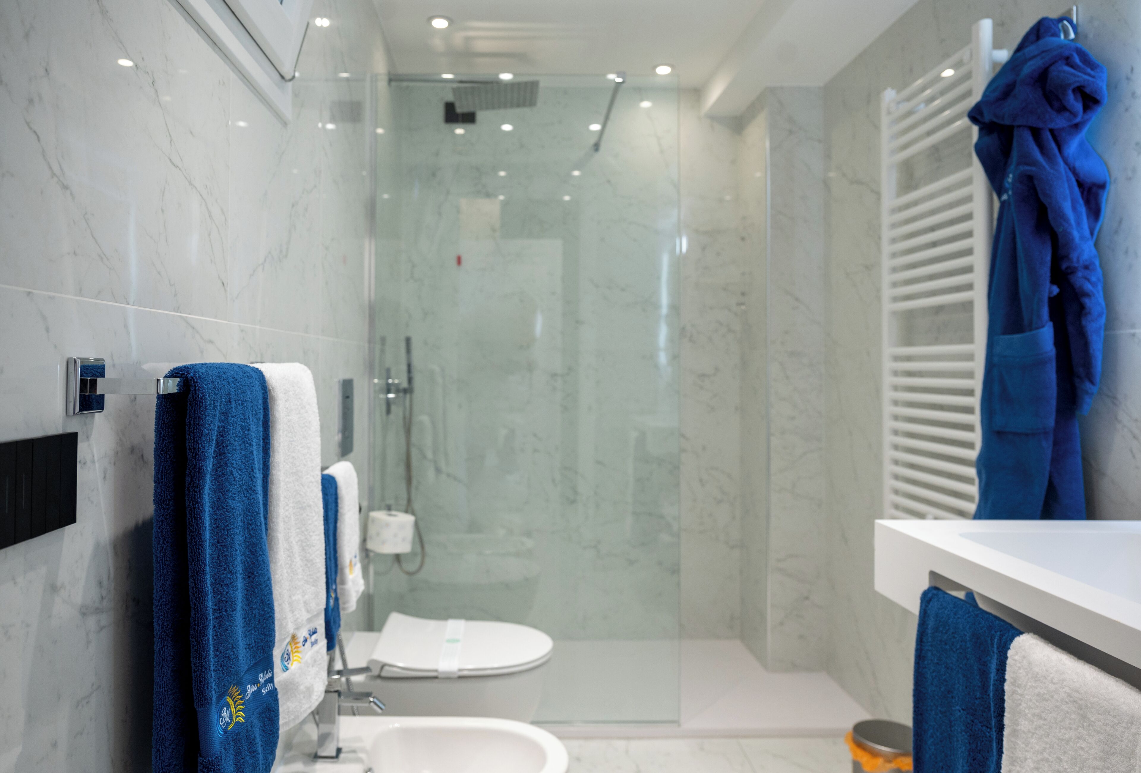 Et moderne badeværelse med et glasbadeværelse, en hvid vask og et toilet.