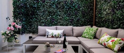 A modern living room with a green leafy wall, a sofa, a coffee table, and decorative pillows.