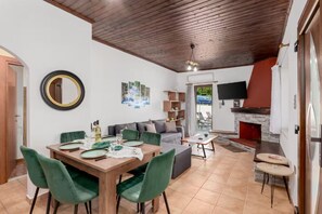 Un comedor con una mesa de madera y sillas verdes, un sofá y una chimenea.