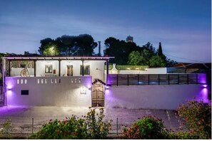 Una casa moderna con un porche cubierto, un jardín vallado y vistas del entorno.