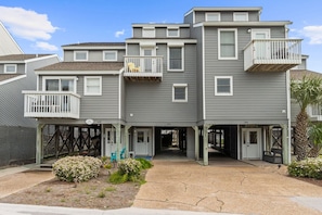 A multi-story residential building with balconies, a front entrance, and a small garden area. - August '26 Rate Drop! Don't Worry, Beach Happy for your next vacation! 3BR/3.5BA (Port St. Joe)