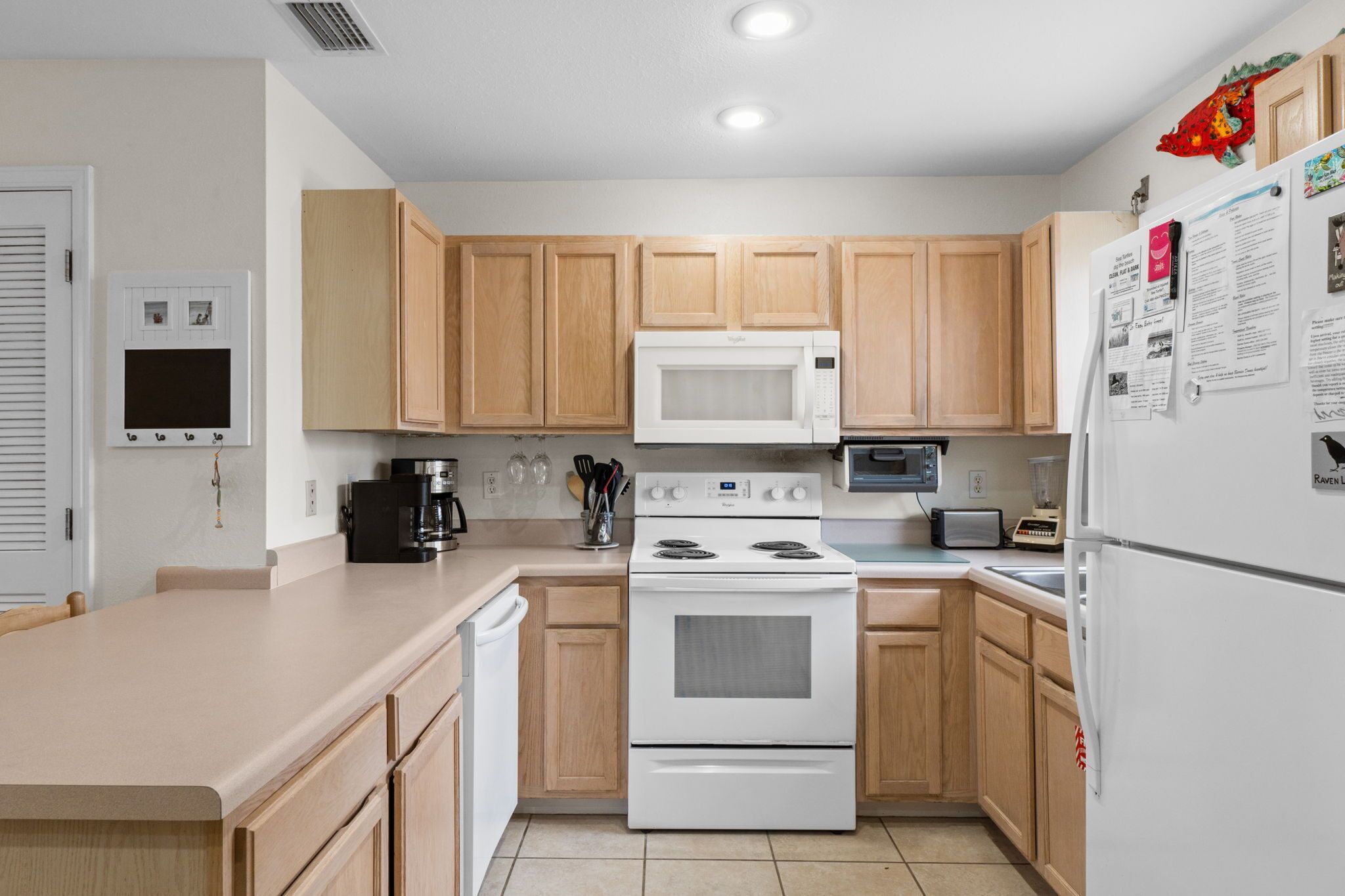 A modern kitchen with wooden cabinets, a white stove, a microwave, and a refrigerator.