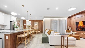Een moderne keuken met een centraal eiland, houten barstoelen en hanglampen.