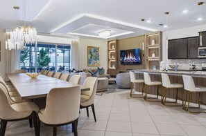 A modern kitchen with a large island, built-in appliances, and a flat-screen TV. - 10BR house at Windsor Cay Resort (Clermont)