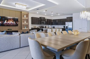 Een moderne keuken met donkere kastjes, een groot eiland en een eethoek met een houten tafel en stoelen.