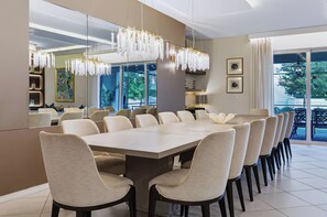 A modern dining area with a large table and chairs, a chandelier, and a view of the outdoors. - 10BR house with private pool and game room (Clermont)